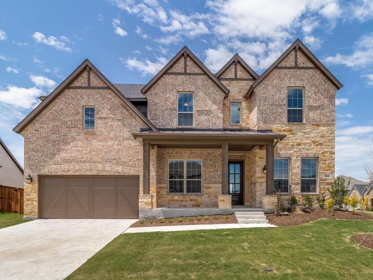 Two-story brick and stone new construction home with a covered front porch in North Texas