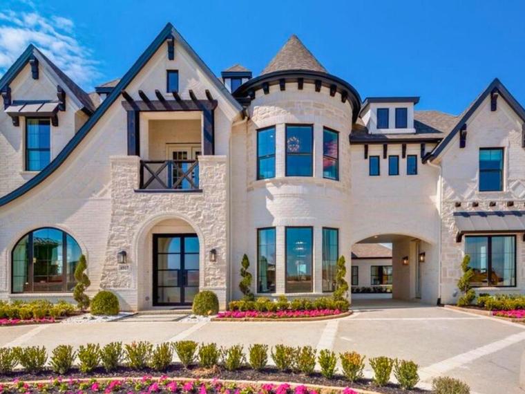 Large white brick model home with turret and formal landscaping in North Texas